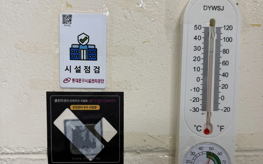 공공도서관 벽면의 시설점검 표지와 NFC 점검 태그, 옆에 온습도계